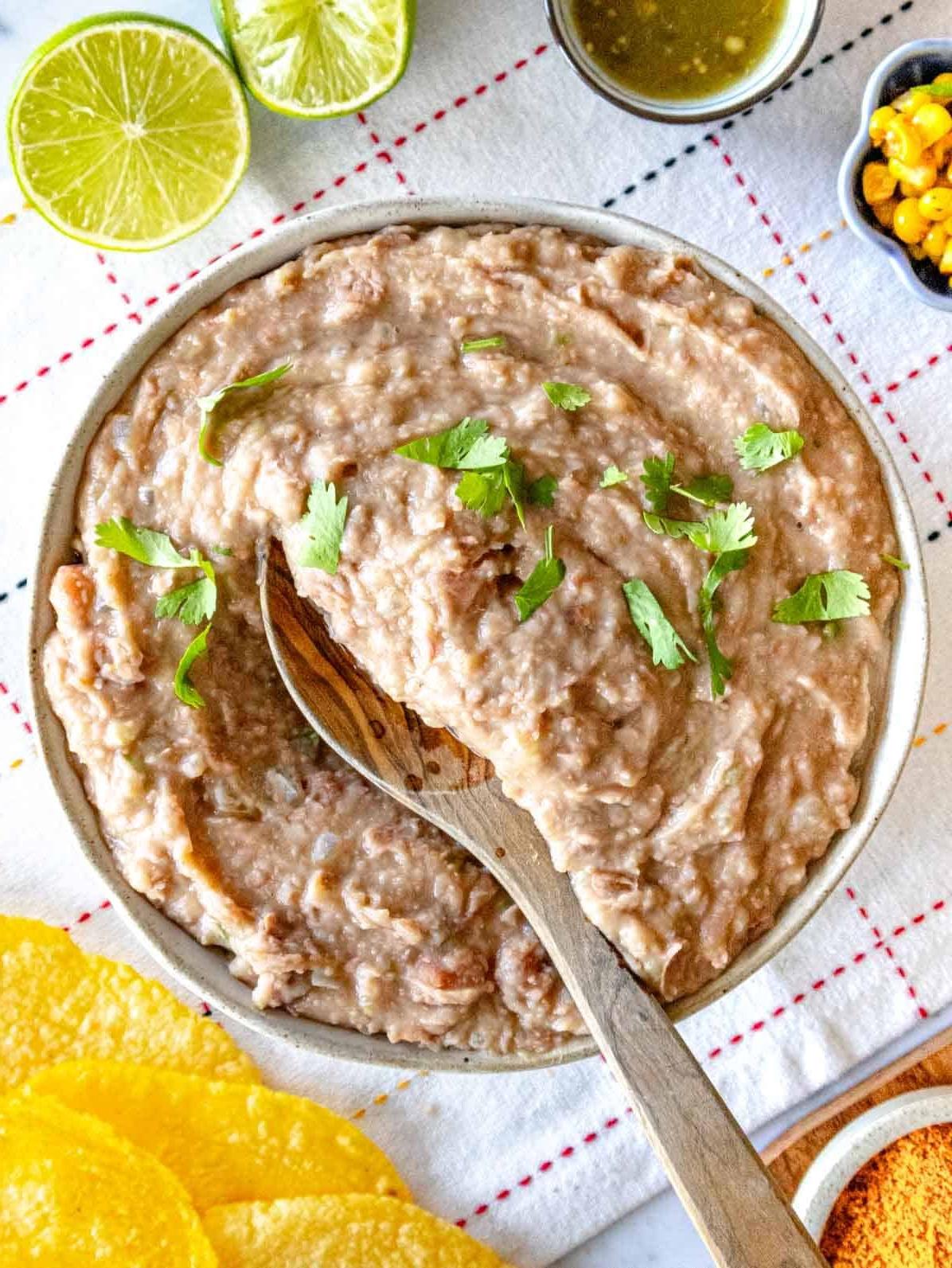 Refried Beans mit Koriander und einem Holzlöffel
