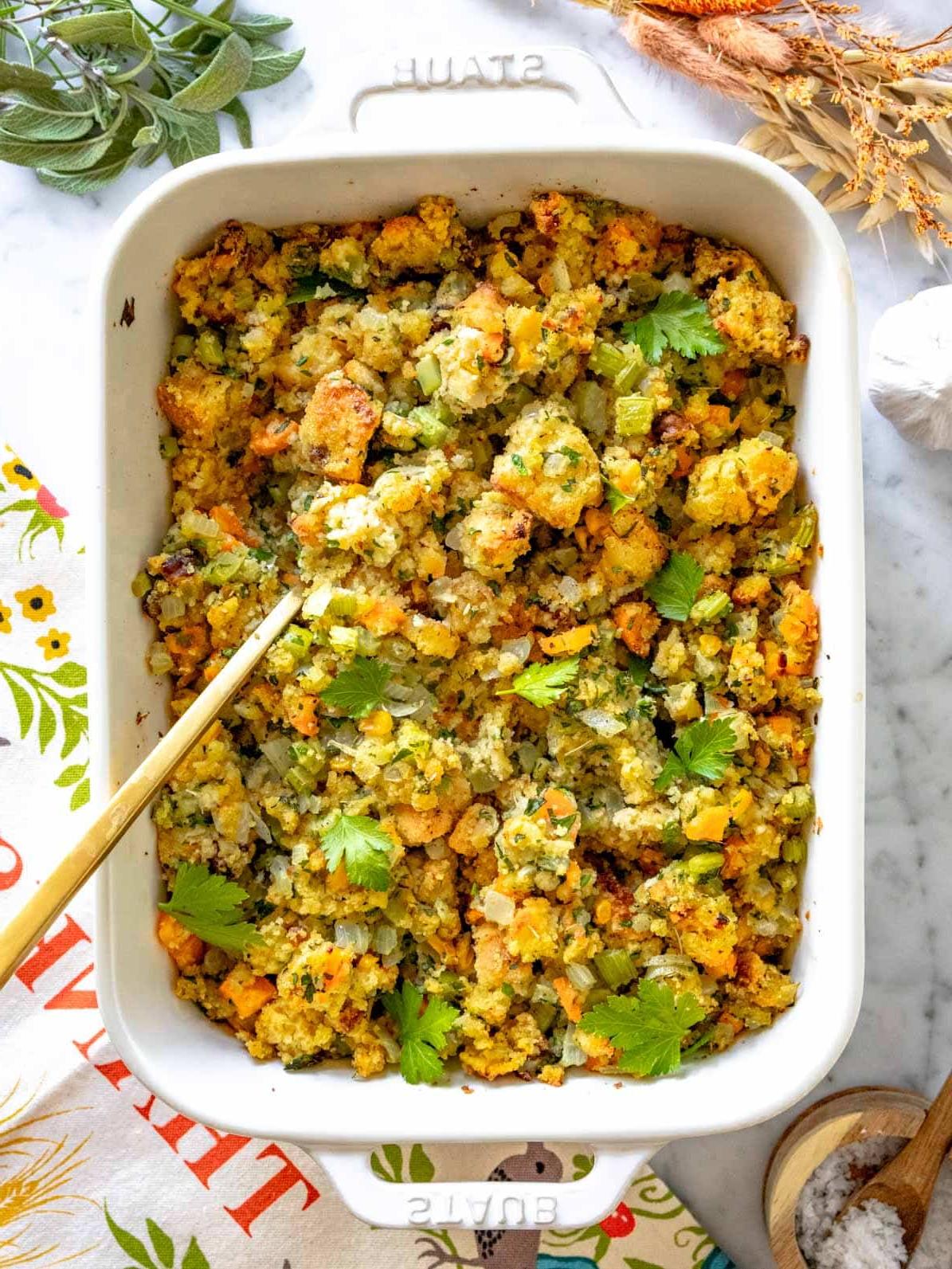 Cornbread Stuffing in einer weißen Auflaufform mit einem goldenen Löffel