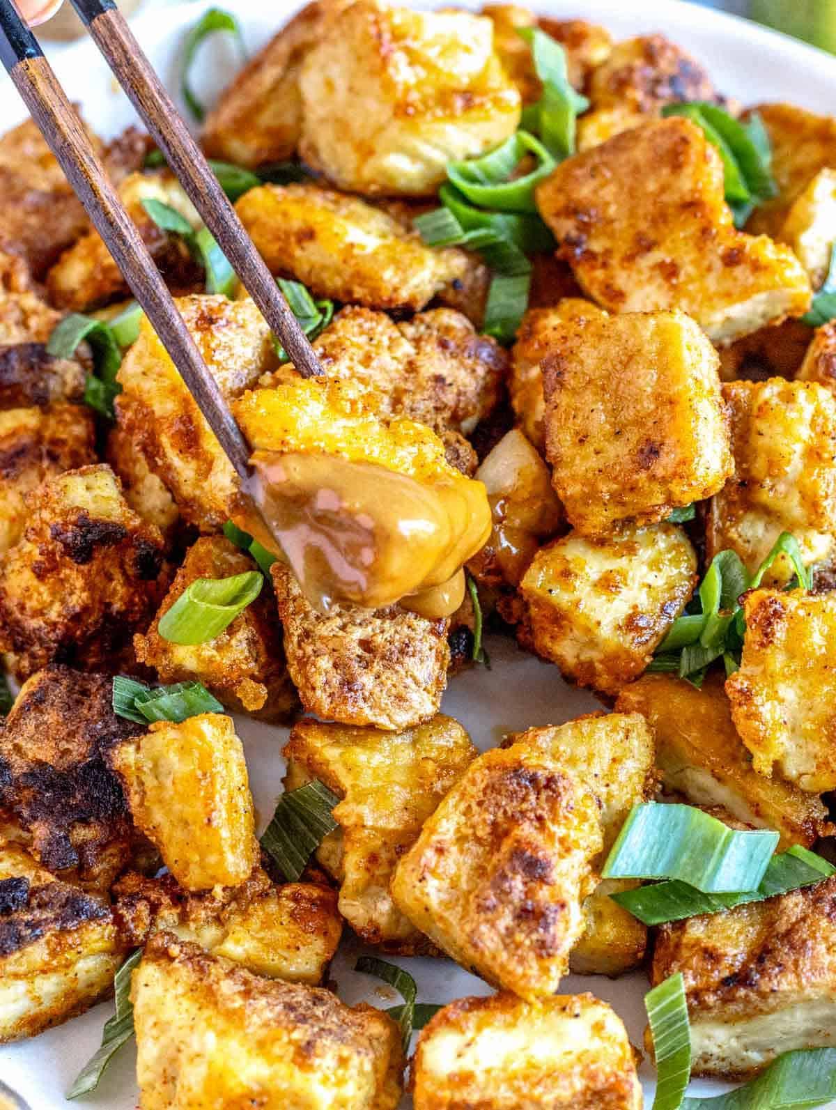 Gebratenes Tofu, in Erdnusssauce getaucht.
