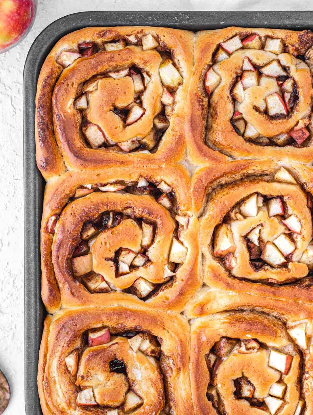 apfel-zimtschnecken mit roten apfelstücken in den spiralen