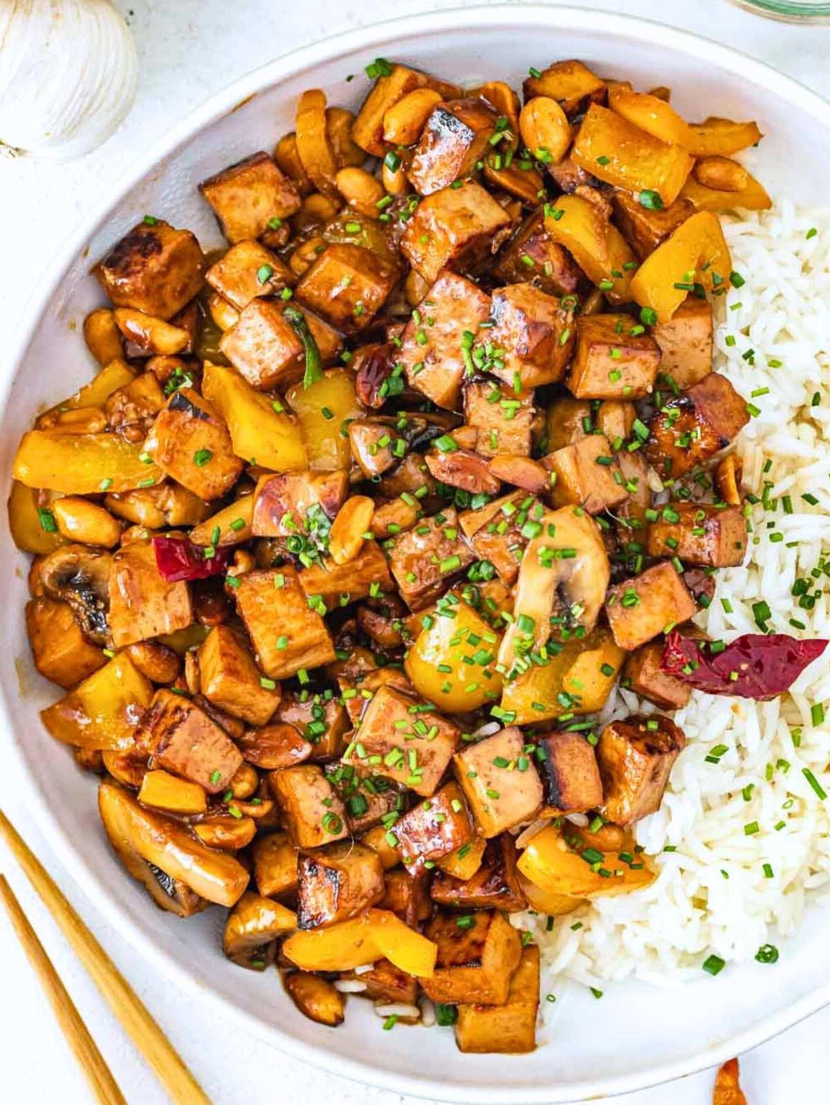 Kung Pao Tofu mit weißem Reis und Essstäbchen.