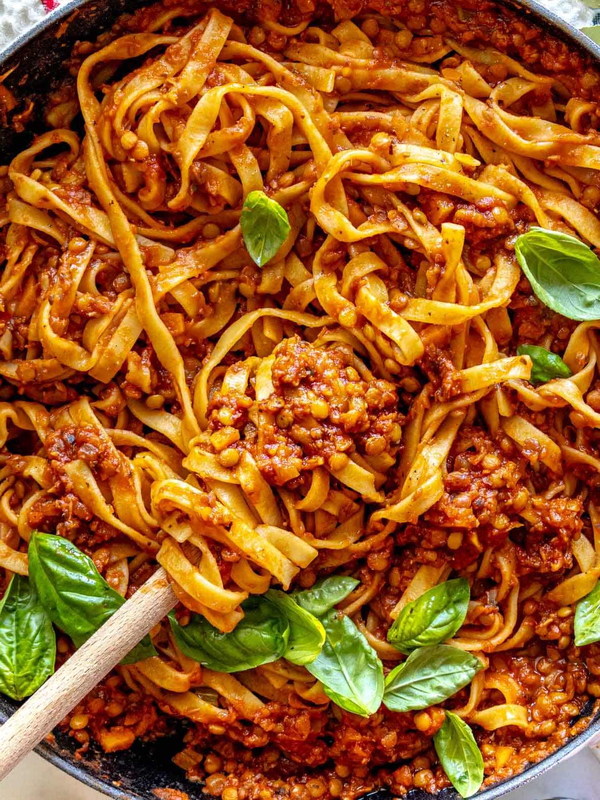 Linsen-Bolognese mit Fettuccine-Pasta in einer schwarzen Pfanne.