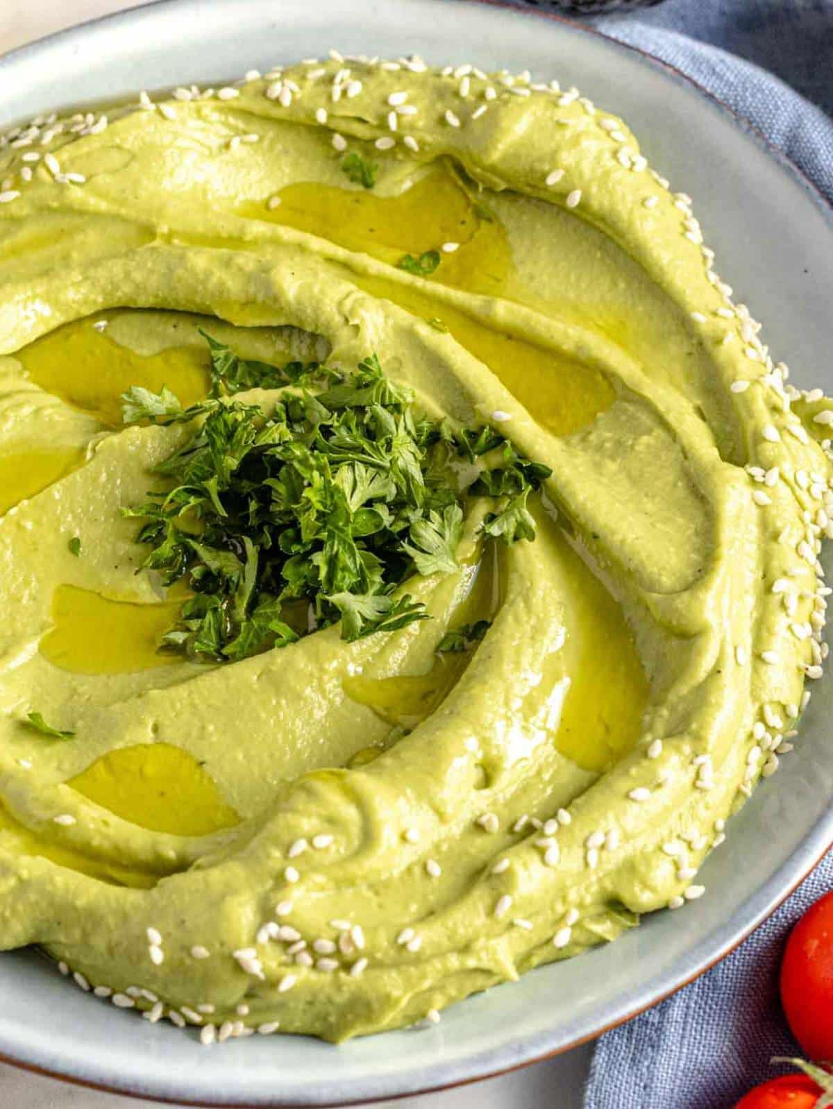 Cremiger Avocado-Aufstrich in einer Schale, garniert mit Kräutern und Olivenöl.