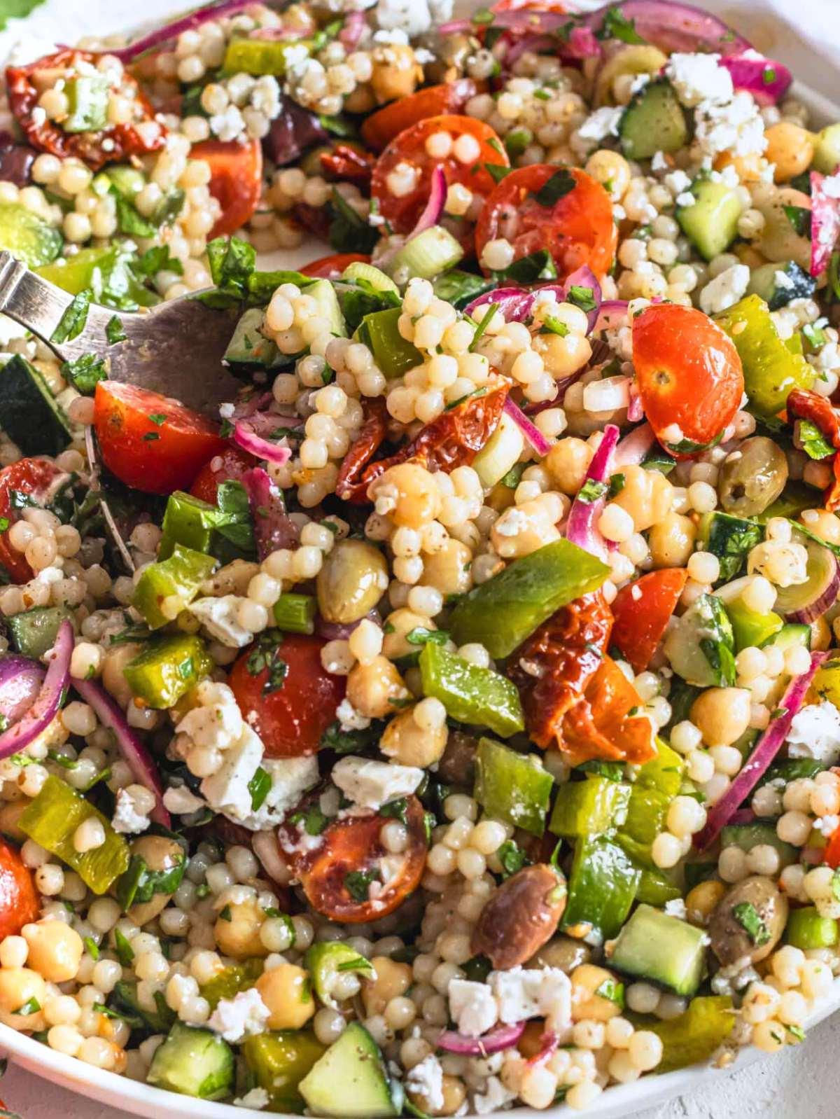 Einladender mediterraner Perlcouscous Salat, reich an frischem Gemüse und Feta.