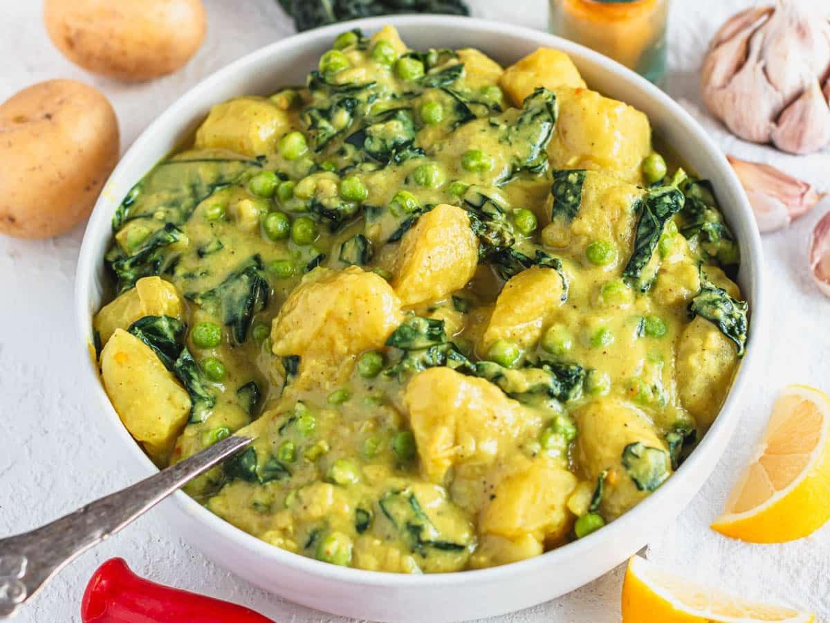 Kartoffel-Curry in einer weißen Schale mit Zitronenspalten daneben