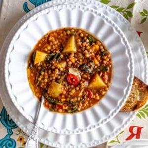 einfache Linsensuppe in einer weißen Schüssel mit Brot und einem Löffel