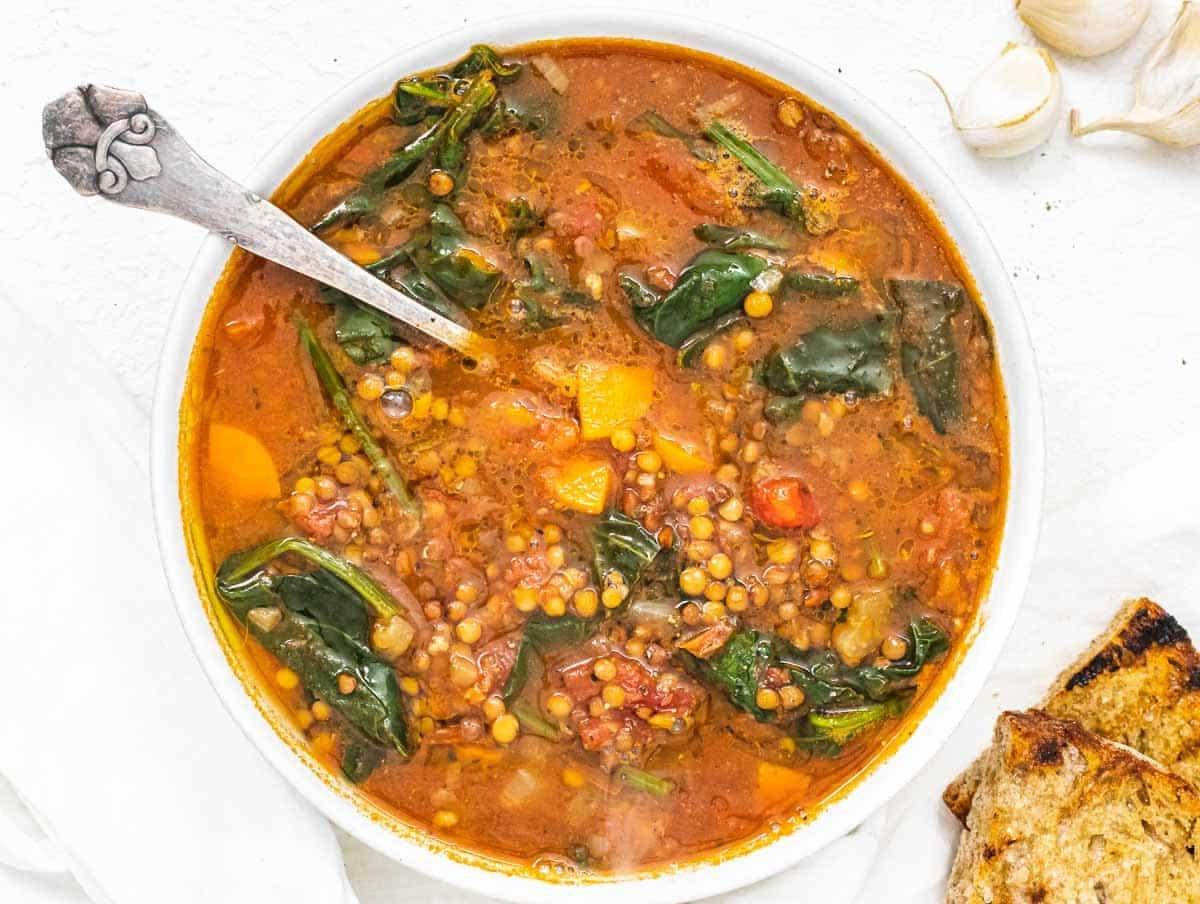 30 vegane Mittagessen-Ideen 11 Linsen-Gemüse-Suppe mit Löffel in einer rustikalen Schüssel