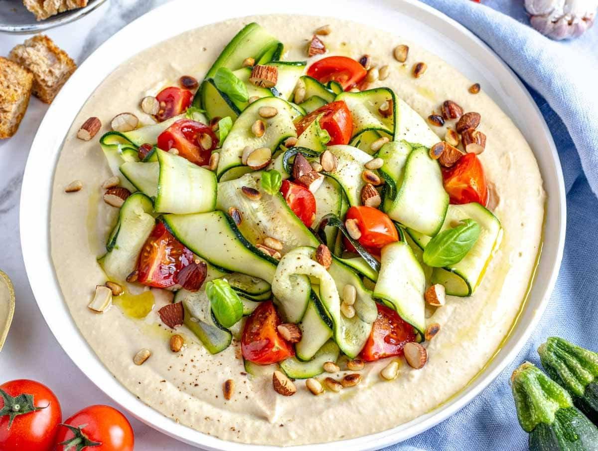 Zucchini-Salat auf einem Bett aus Hummus serviert.