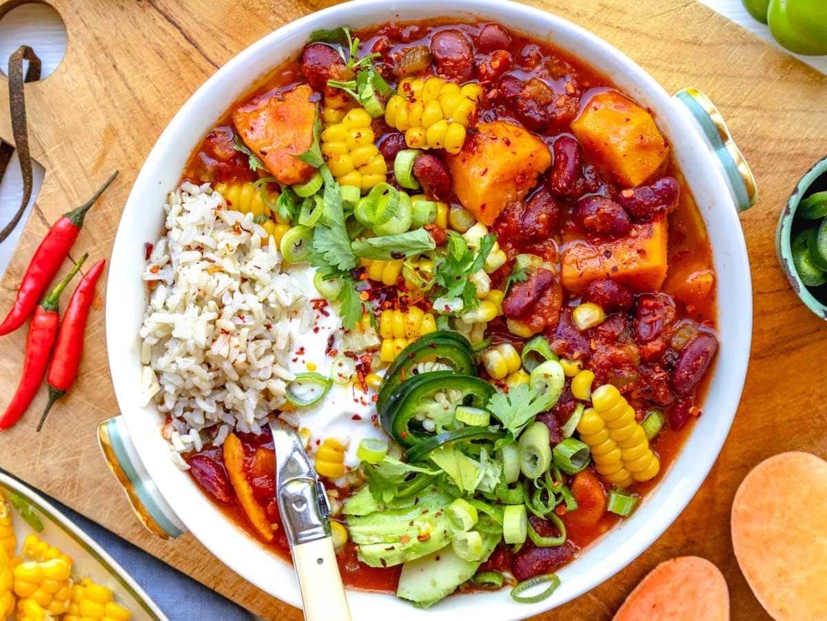 sweet potato chili in a bowl topped with corn, lime, and cilantro