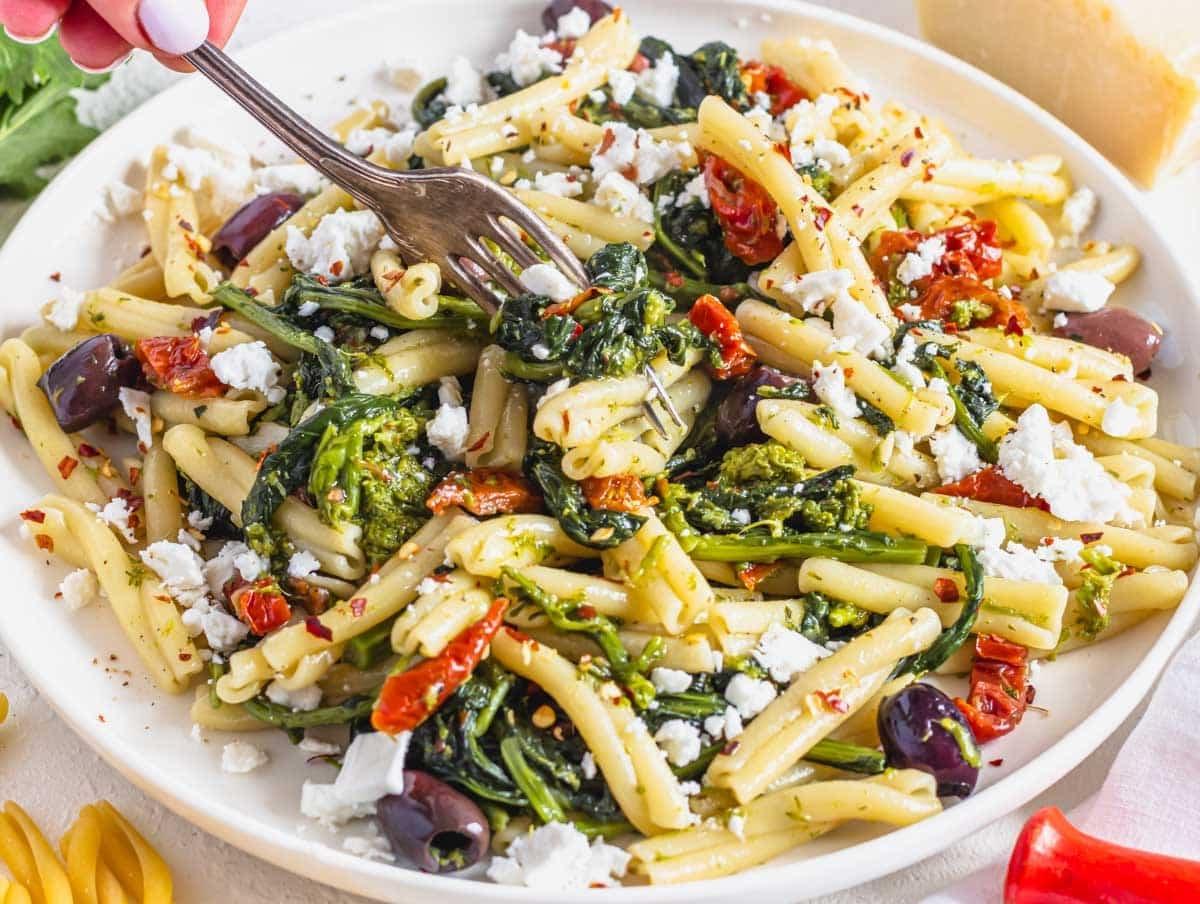 Casarecce-Pasta mit einer Hand, die eine silberne Gabel hält
