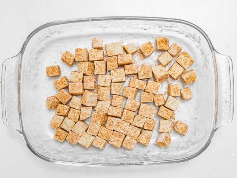 Gewürfelten Tofu in der Gewürzmischung wenden, um ihn zu bedecken.