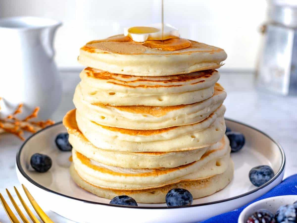 Vegane Pancakes mit Blaubeeren und einer Scheibe veganer Butter.