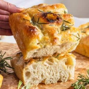 Focaccia mit Rosmarin und eine Hand, die ein Stück hält.