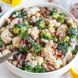cauliflower broccoli salad with sundried tomatoes and a silver spoon