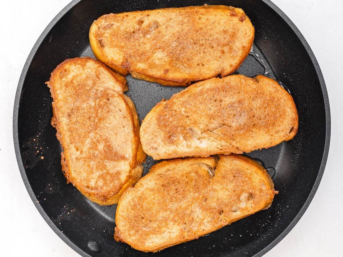 cinnamon batter covering 4 slices of bread in a skillet