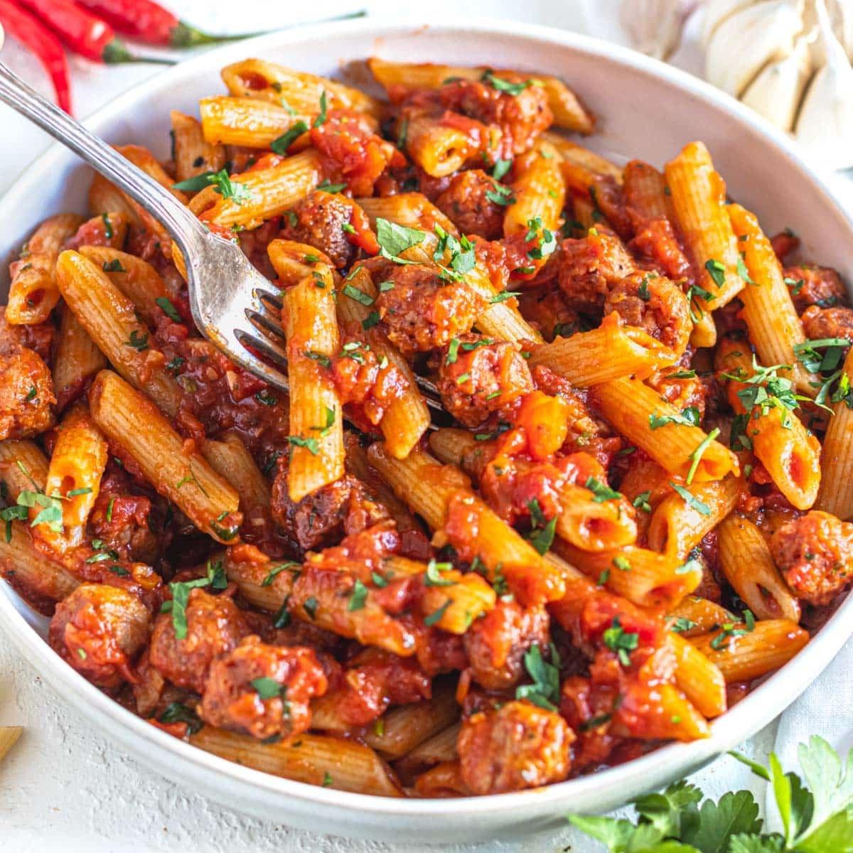 Penne mit Arrabbiata-Sauce und einer silbernen Gabel in der Pasta.