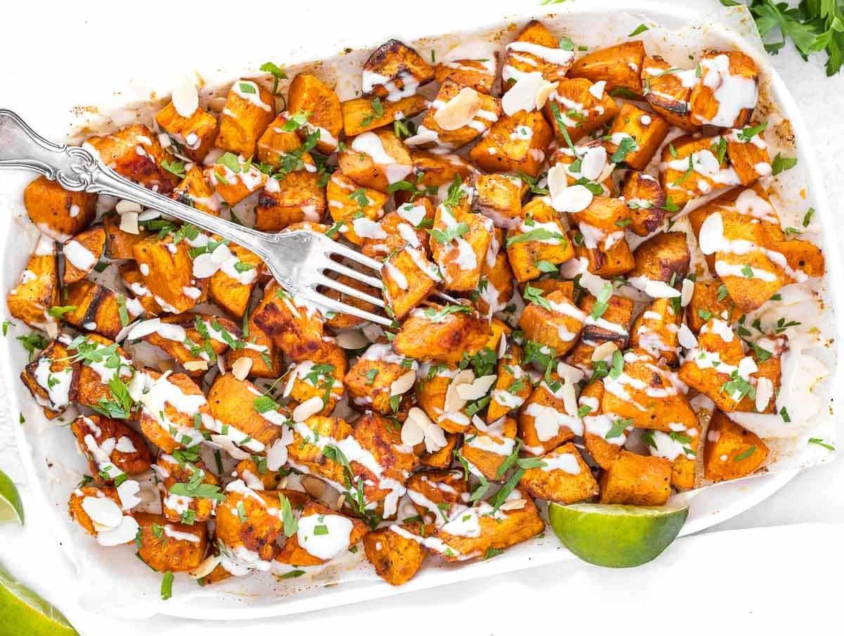 geröstete Süßkartoffelwürfel mit Tahinisauce und Petersilie beträufelt