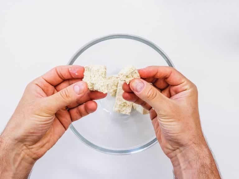 Tofu mit Händen auseinanderbrechen.