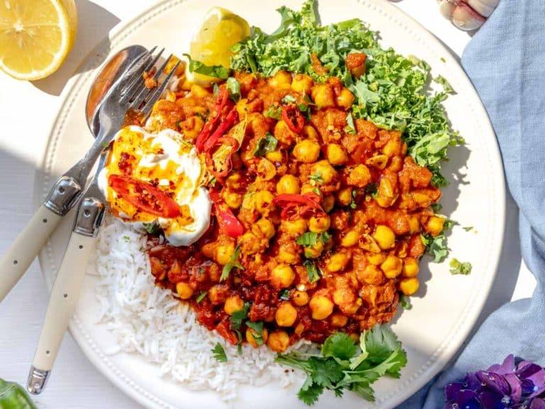 Chana Masala auf einem Teller mit Grünkohl, Joghurt und Chiliöl
