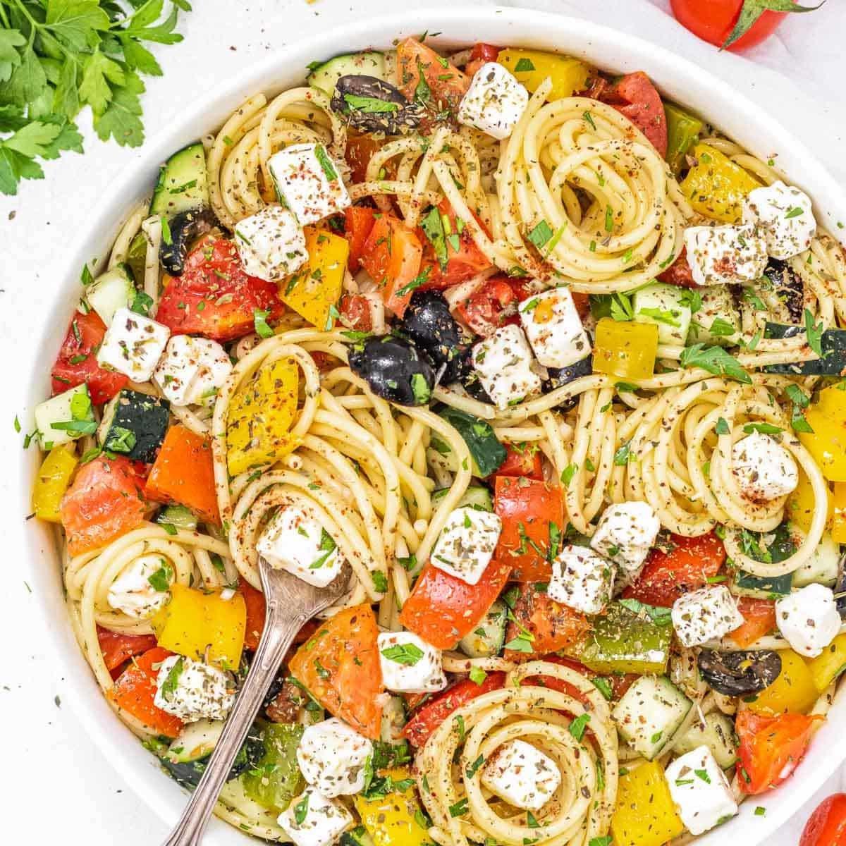 Spaghetti-Salat mit einer Gabel und schwarzen Oliven, frisch zubereitet.
