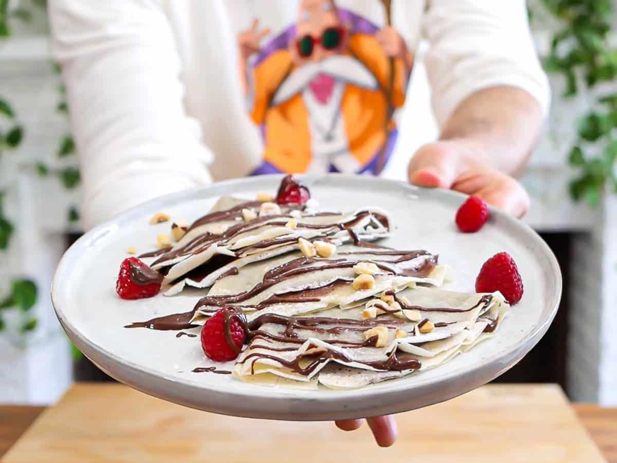 Vegane Crêpes auf einem Teller mit Beeren und hausgemachtem Haselnussaufstrich