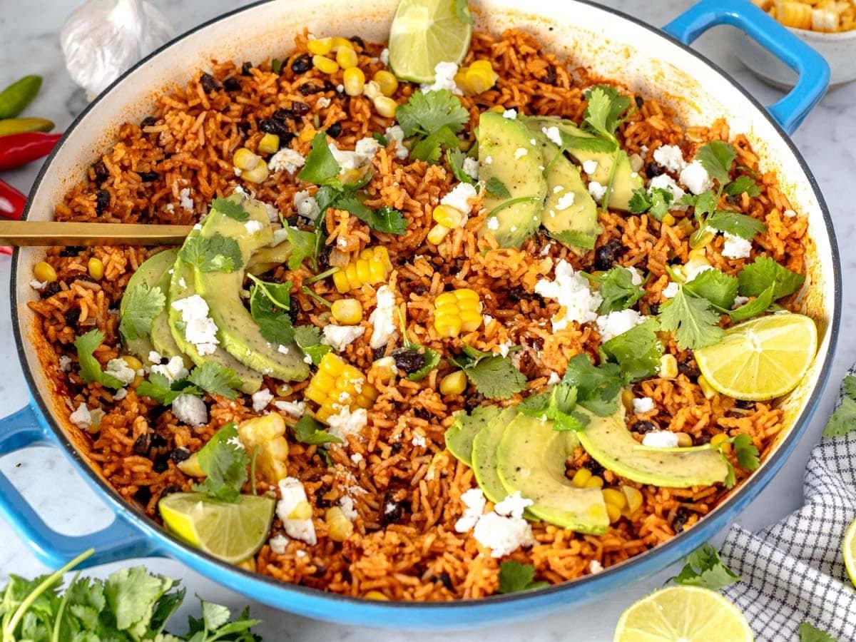 Mexican rice in a blue skillet with a golden spoon