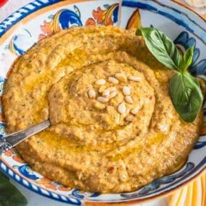 Rotes Pesto in einer blauen Schüssel mit einem silbernen Löffel