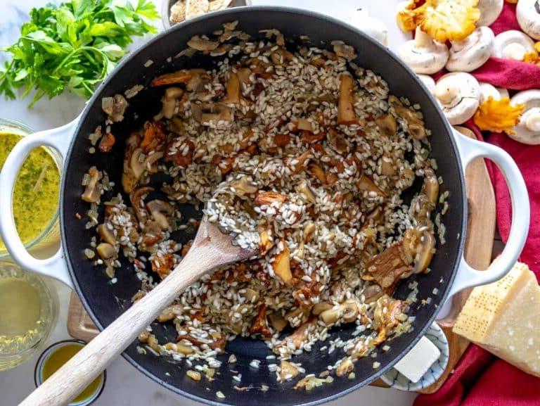 Risottoreis zum Topf mit Pilzen hinzufügen