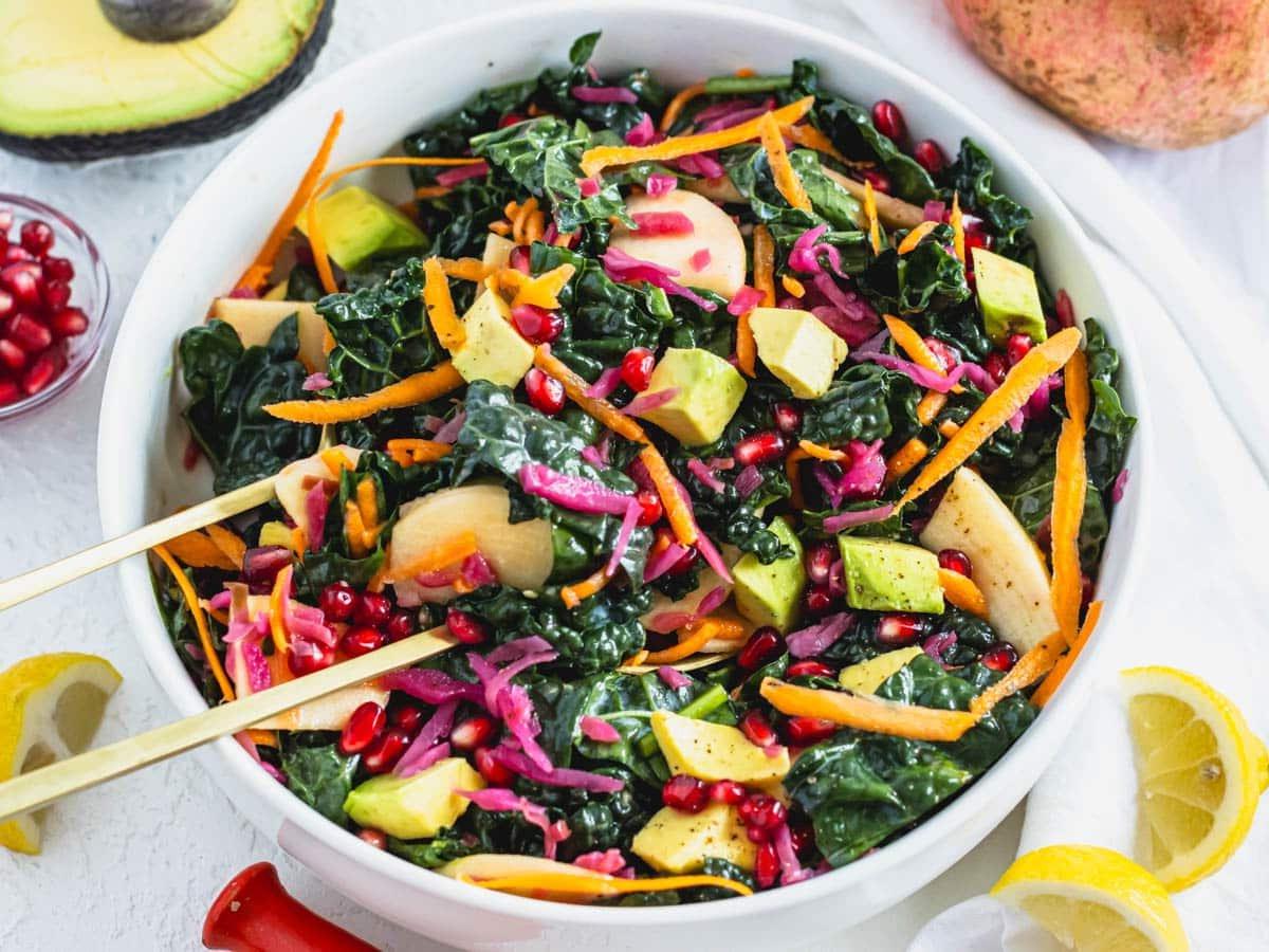 25 Avocado Rezepte 15 Grünkohlsalat in einer weißen Schüssel mit Zitronen und Avocado daneben