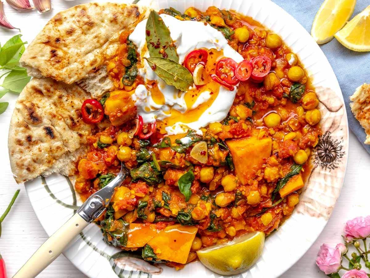 Kichererbsen-Eintopf mit Joghurt und Chili-Öl auf einem Teller mit Blumen
