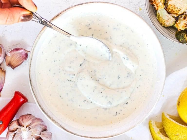 Veganes Ranch Dressing mit Hand und Silberlöffel