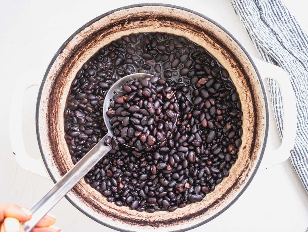 black bean after cooking in a white pot and a silver spoon