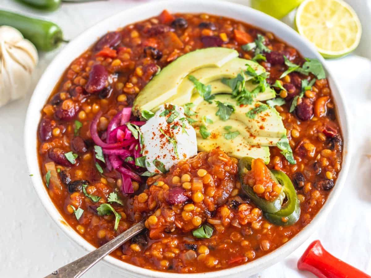 25 Avocado Rezepte 16 Linsen-Chili in einer weißen Schüssel mit Avocado und eingelegten roten Zwiebeln