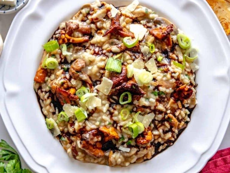 Pilzrisotto garniert mit gehobeltem Parmesan, Lauchzwiebeln und Balsamico-Glasur