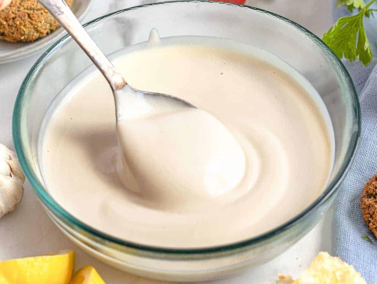 Cremige Tahini-Sauce in einer Glasschale mit einem silbernen Löffel