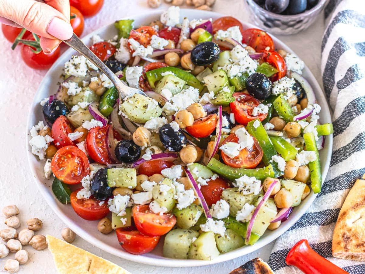Griechischer Kichererbsen-Salat auf einem weißen Teller mit zerbröseltem Feta.