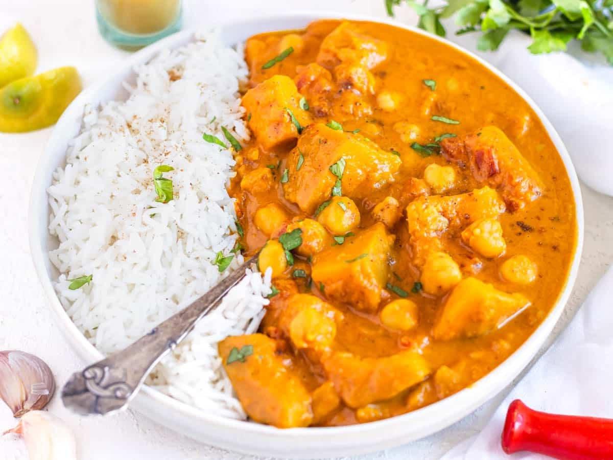 Kürbis-Curry mit Reis, Löffel und frischer Petersilie