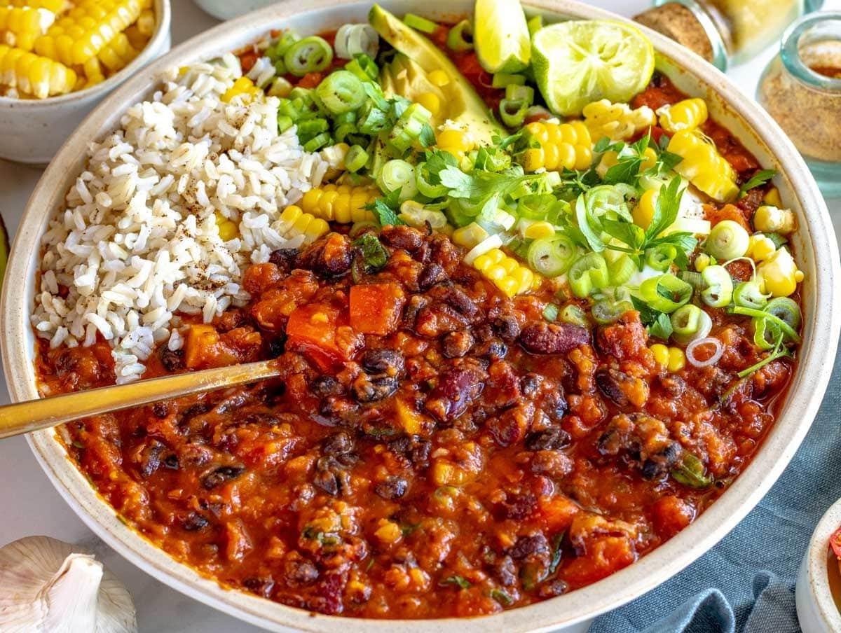 Vegetarisches Chili mit braunem Reis, Maiskolben und Limette
