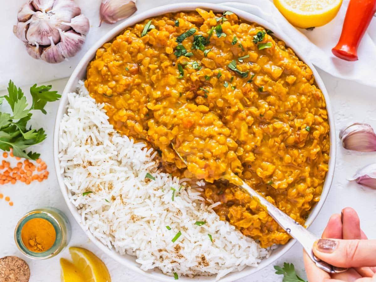 Linsen-Curry-Rezept mit Reis und einer Hand