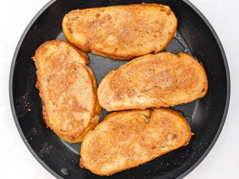 cinnamon batter covering 4 slices of bread in a skillet