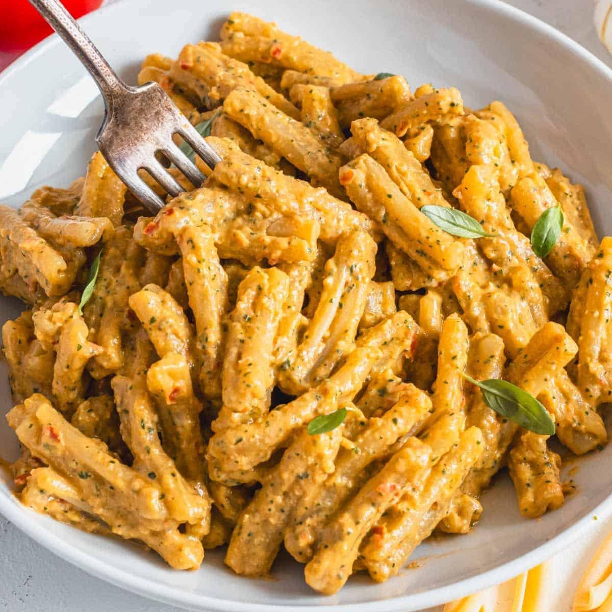 Cremige Tomaten-Pasta mit frischem Basilikum und einer Gabel.