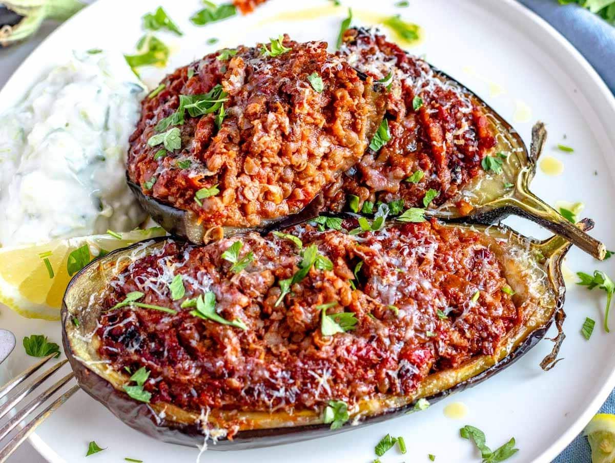 Gefüllte Aubergine, aufgeschnitten auf einem Teller mit Tzatziki