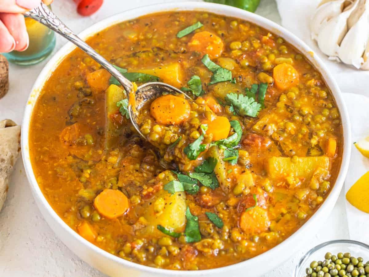 Mungbohnen-Suppe mit einem silbernen Löffel und frischem Koriander