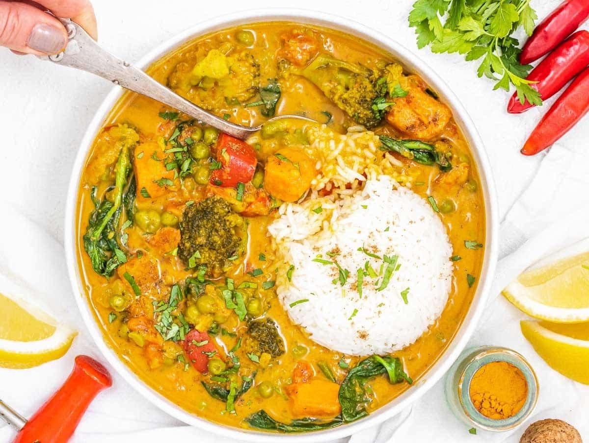 Gemüse-Curry mit Löffel und Hand