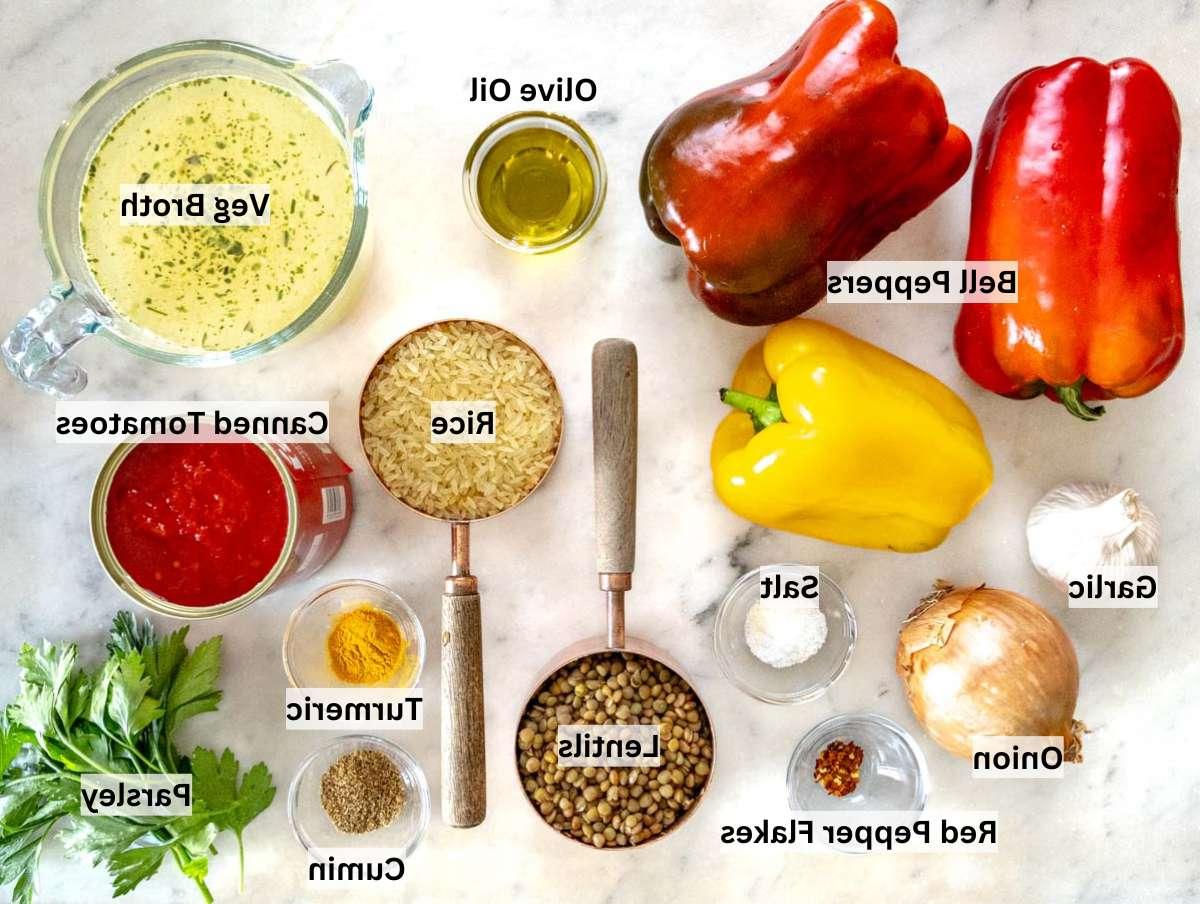 Zutaten für gefüllte Paprika auf einem Marmortisch ausgebreitet.