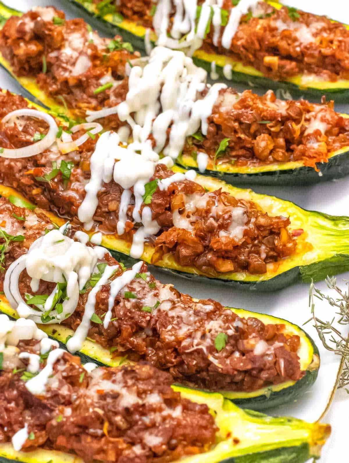 Zucchini-Boote 3 Frisch gebackene Zucchiniboote, serviert mit einem Klecks Sauerrahm.