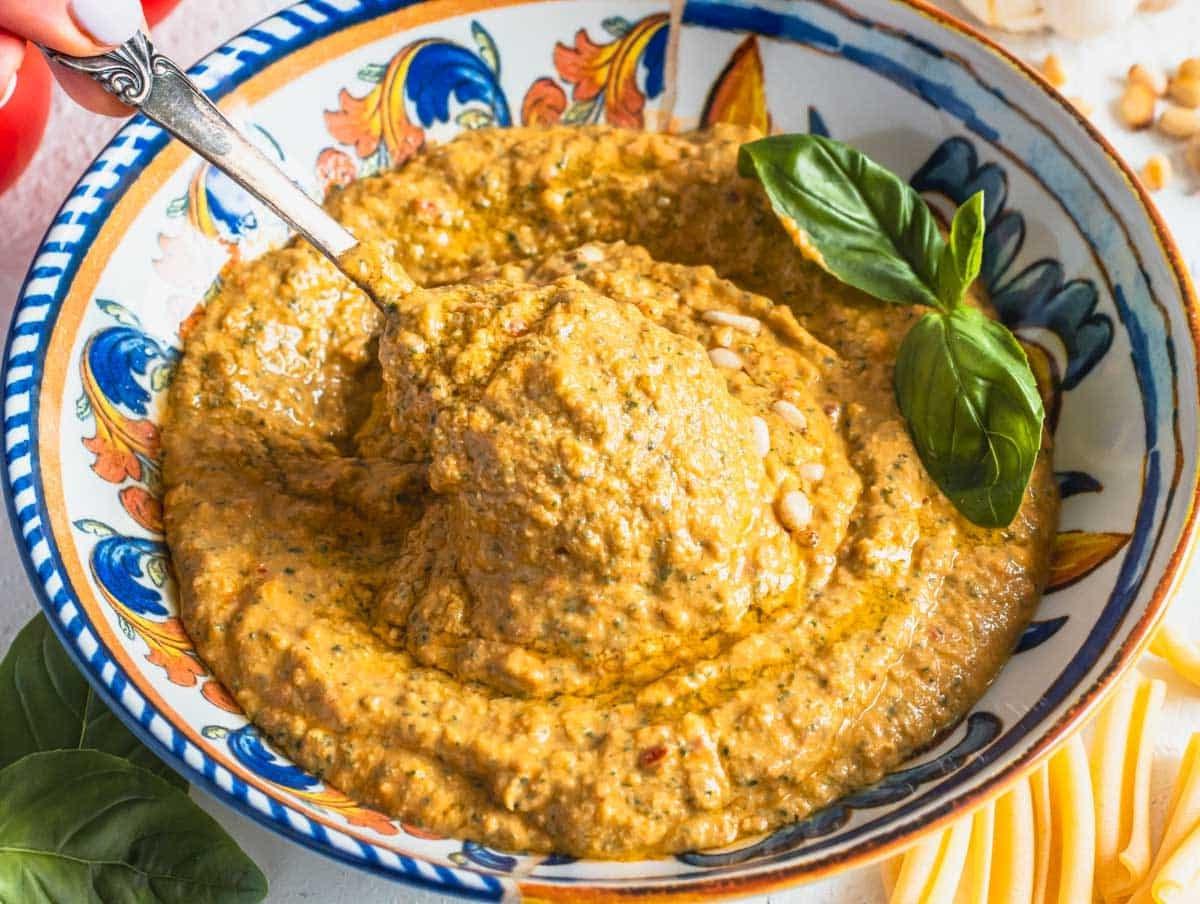 Rotes Tomatenpesto in einer Schüssel mit einem silbernen Löffel