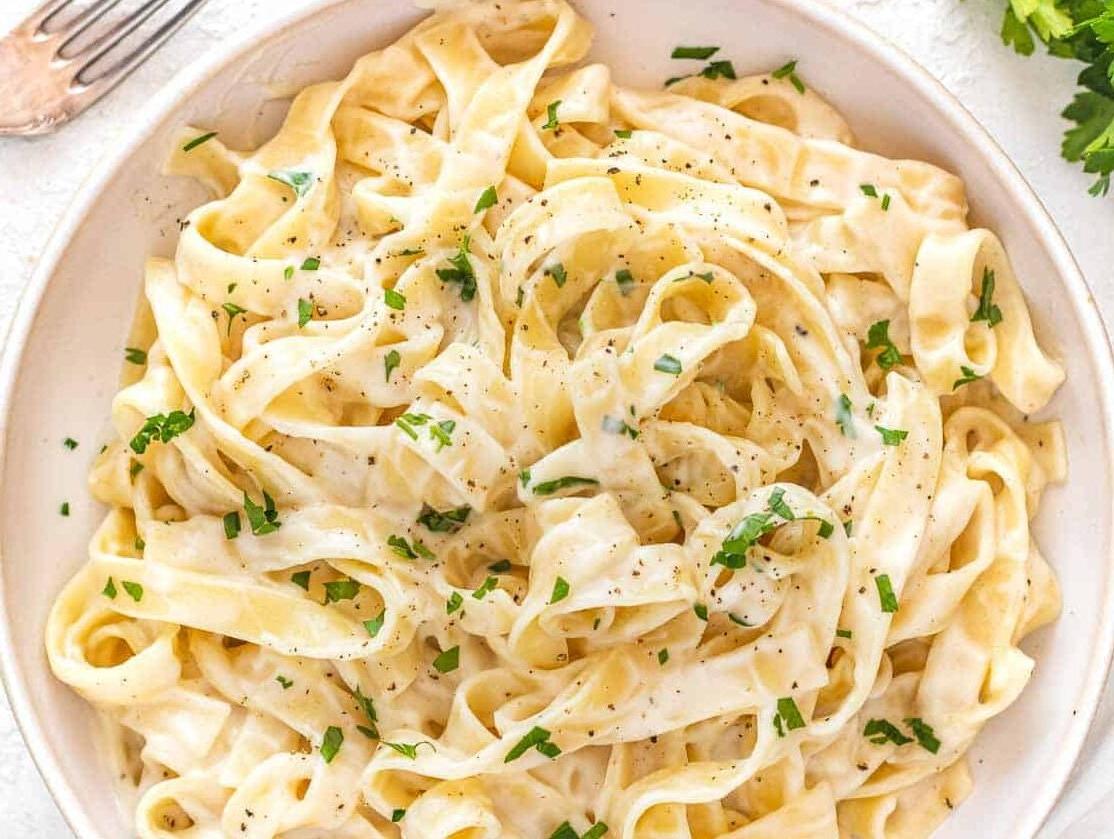 Cremiges Blumenkohl Alfredo in einer weißen Schüssel, fertig zum Genießen – ein leichtes und gesundes Pasta-Rezept.