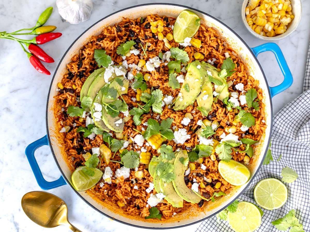Mexikanischer Reis in einer blauen Pfanne mit Mais und Avocado