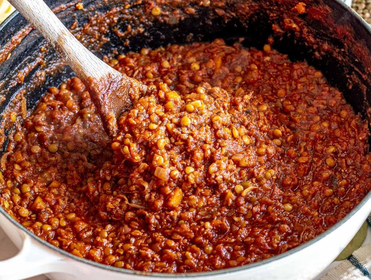 Linsen-Bolognese in einem gusseisernen Topf mit Holzlöffel